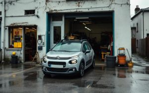 Citroën C3 essence garée devant un atelier, ambiance photo reportage mécanique, lumière naturelle et style éditorial automobile.